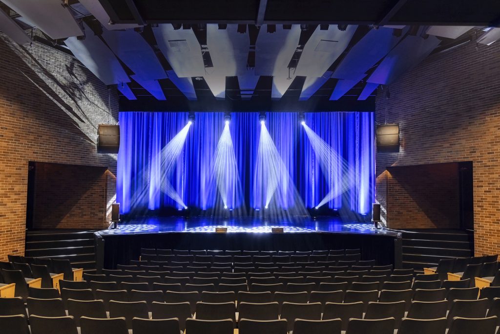 XYZ Technologies Theatre du Cuivre Wide angle view of the stage and seating area lit with professional blue and white lighting Modernisation du système audio du Théâtre du Cuivre
