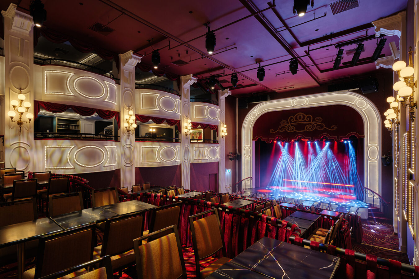 XYZ Technologies CafConc Wide view of the cabaret style theatre with stage lit in red and blue Au coeur du café concert